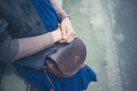 A young woman with a handbag outside in the cityの写真素材