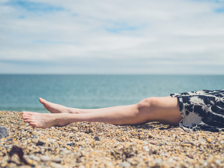 The legs of a young woman as she is lying on the beach in the summerの写真素材