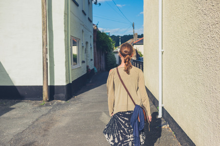 A young woman is walking outside in a small townの写真素材