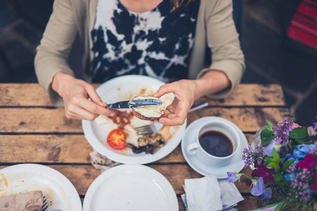 A young woman is having a traditional english breakfast in a cafeの写真素材