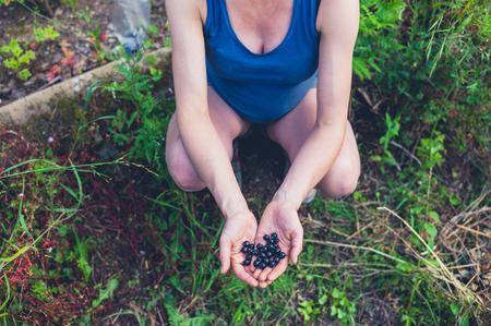 A young pregnant woman is sitting in her garden by a black currant bushの写真素材