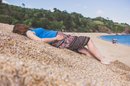 A young woman is lying on the dunes on the beach in summerの写真素材