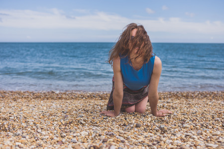 A beautiful young woman is crawling on the beachの写真素材