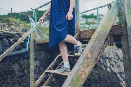 A young woman is walking down some rusty stairs outsideの写真素材