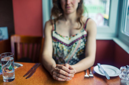 A young woman is sitting in a restaurant and is waiting for her lunchの写真素材