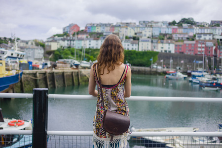 A young woman is standing by the railing in a small harborの写真素材