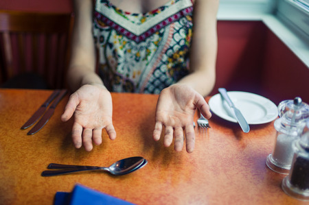 A young woman is sitting in a restaurant and is showing her dirty handsの写真素材