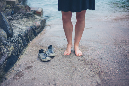 A barefoot woman standing on slipway with her shoesの写真素材