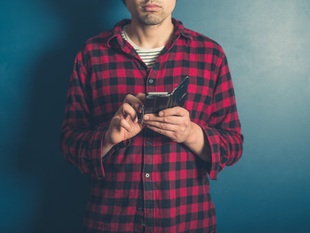 A young hipster man wearing a lumberjack shirt is using his smart phone