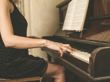 A young woman in a dress is playing the pianoの写真素材