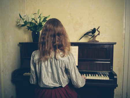 Vintage filtered shot of a young woman playing the pianoの写真素材