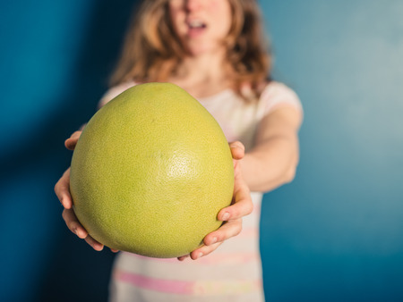 A young woman is holding a big pomeloの写真素材