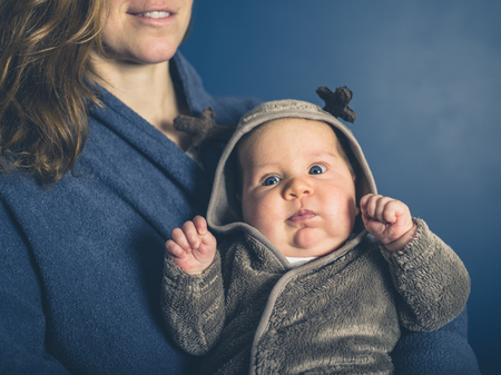 A young mother is holding her baby wearing a reindeer costumeの写真素材