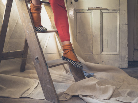 The feet and legs of a young woman sitting on a stepladder