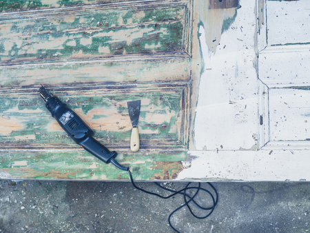A heat gun and a scraper knife on an old door outsideの写真素材
