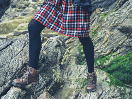The legs of a young woman wearing a skirt standing on some rocks in natureの写真素材