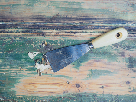 A scraper knife ona wooden surace with paint flakesの写真素材