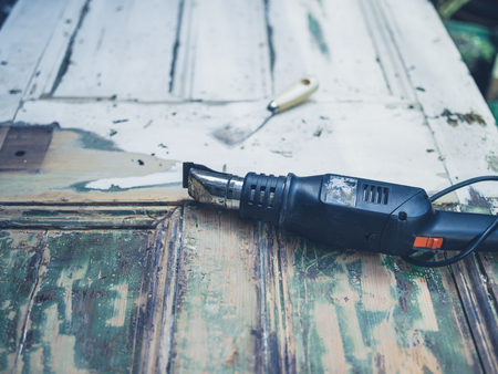 A heat gun and a scraper knife on an old door outsideの写真素材