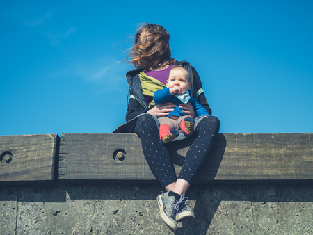 A young mother is relaxing with her baby outsideの写真素材