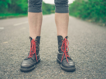 The feet of a young woman wearing boots with red laces outdoors