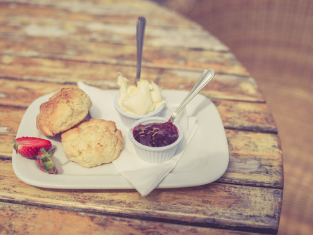 Vintage filtered shot of cream tea with scone and jam on a tableの写真素材