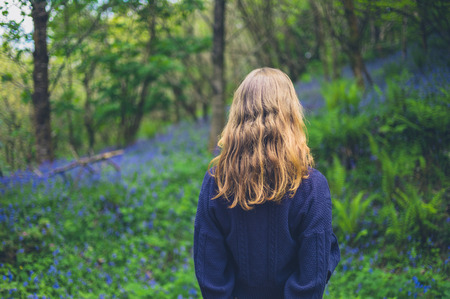 A young woman is standing in a meadow of bluebellsの写真素材