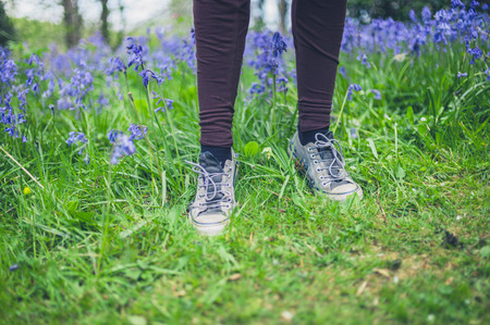 The feeat of a young woman standing in a meadow of bluebellsの写真素材