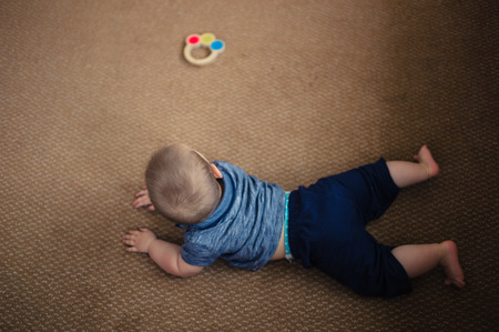 A little baby is playing with a rattle on the living room floorの写真素材