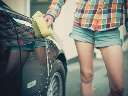 A young woman is soaping and washing her carの写真素材