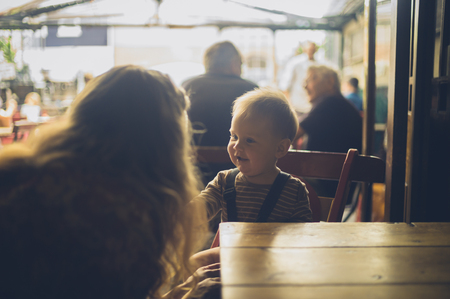 A young mother is sitting at a table in a cafe with her babyの写真素材