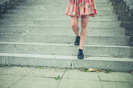 The legs of a young woman as she is walking down some stairs outside in the cityの写真素材