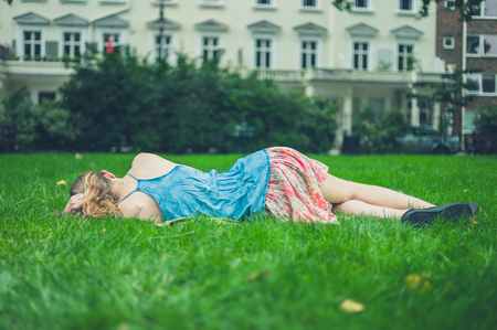 A young woman is relaxing on the grass in a park on a summer dayの写真素材