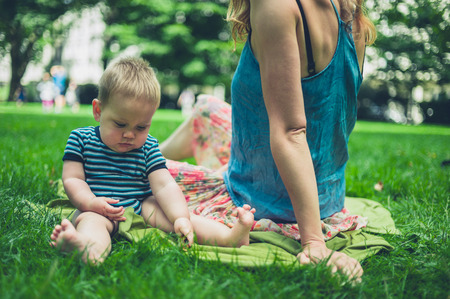 A young mother is sitting on the grass with her baby on a summer dayの写真素材