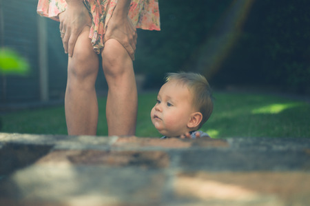 A young mother is standing with her baby in the garden at sunsetの写真素材