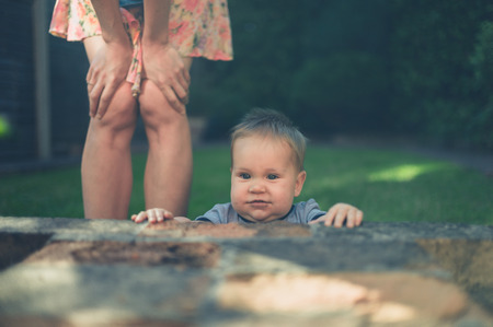 A young mother is standing with her baby in the garden at sunsetの写真素材