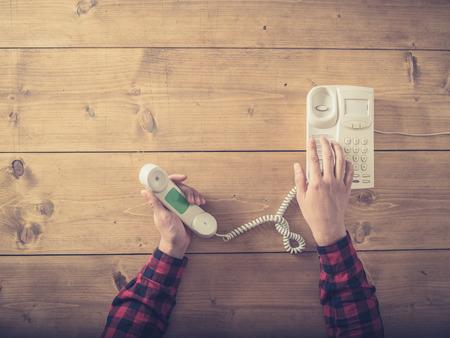 Overhead shot of a man at a table using an old phone to make a callの写真素材