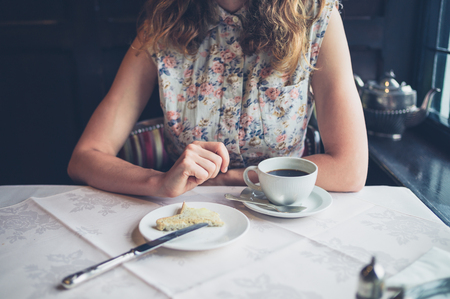 A young woman is eating toast with butter at a dining tableの写真素材