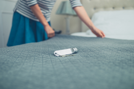 A hotel room key on the bed with a woman making the bedの写真素材