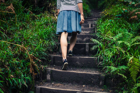 A young woman is walking up some steps in the forestの写真素材