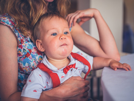 A young mother and her baby are relaxing at a dinner, table
