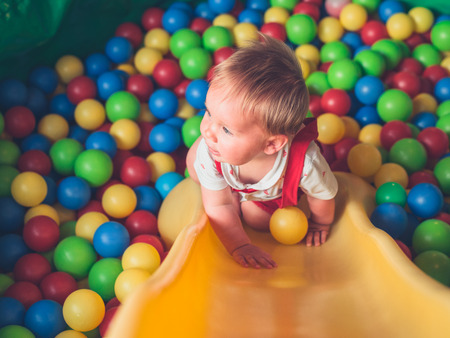A cute little baby is playing in a pool of ballsの写真素材