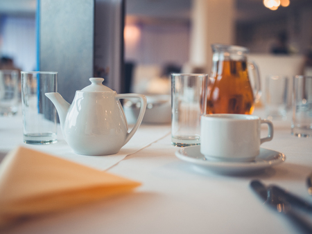 A teapot and cup on a table set for breakfastの写真素材