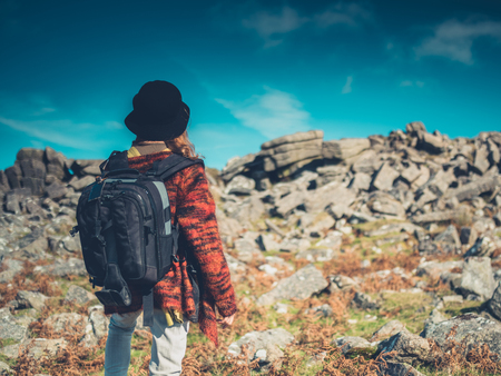 A young woman wearing a backpack is trekking through the wildernessの写真素材