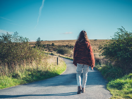 A young woman is walking on a road in the wildernessの写真素材