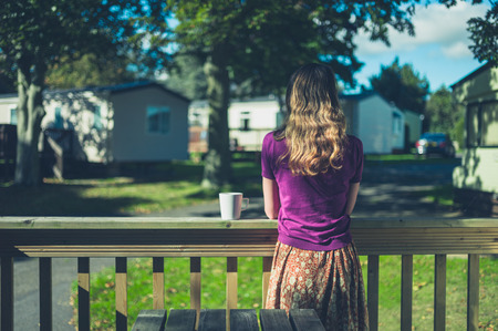 A young woman is drinking tea or coffee in a trailer parkの写真素材
