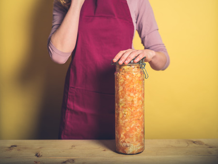 A young woman is holding a massive jar of ultra delicious homemade kimchiの写真素材