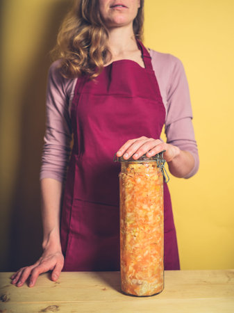 A young woman is holding a massive jar of ultra delicious homemade kimchi
