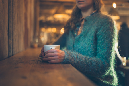 A young woman is drinking coffee in a cafeの写真素材