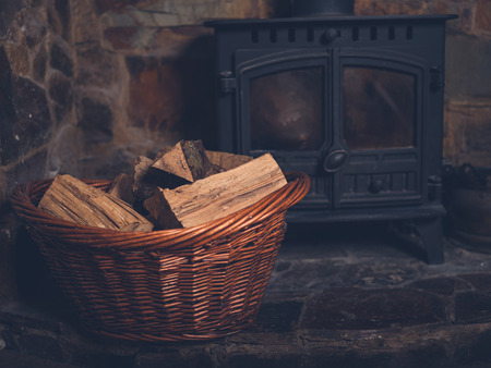 A basket full of firewood by a log burnerの写真素材