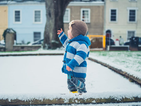A little toddler is exploring a playground in the snowの写真素材